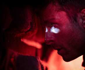 Ben Richards (Glen Powell), in a dim, red-lit car trunk, peers through a bullet hole to the outside in the 2025 adaptation of Stephen King's The Running Man