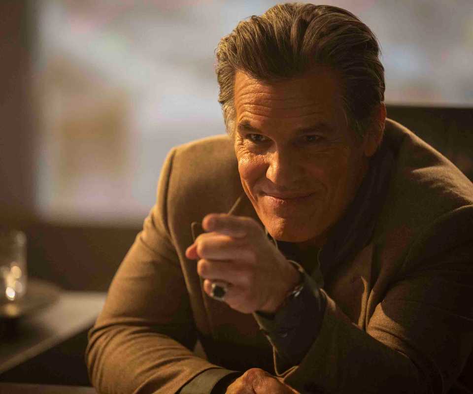 Killian (Josh Brolin) smirks and points across a desk in The Running Man 2025