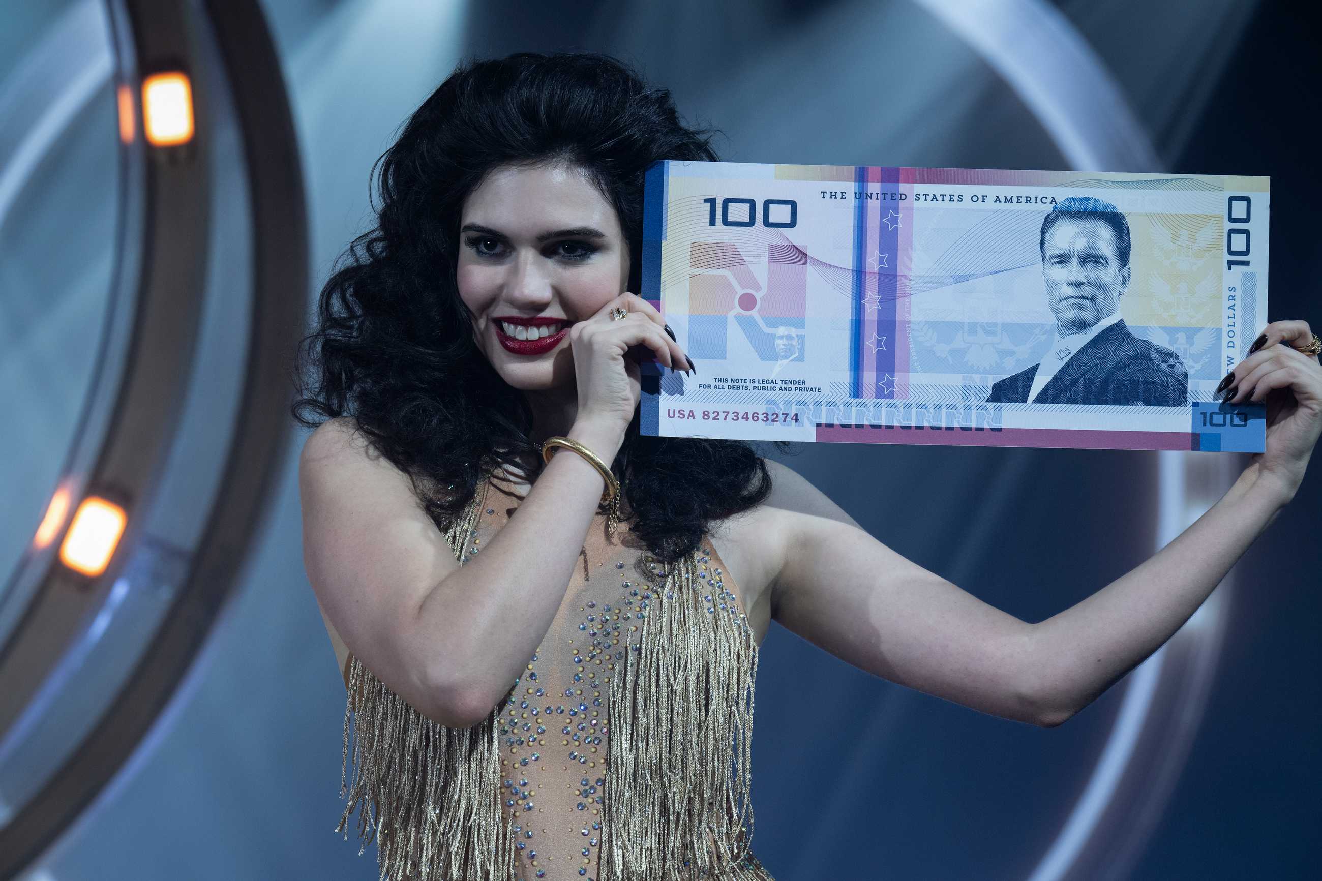 Model holding "new dollar" with Arnold Schwarzenegger's face in The Running Man