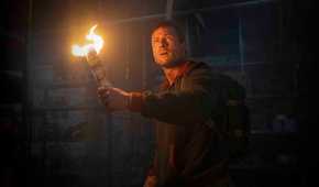 Glen Powell holds a DIY torch up in The Running Man