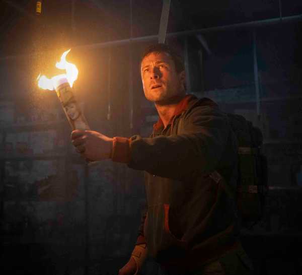 Glen Powell holds a DIY torch up in The Running Man
