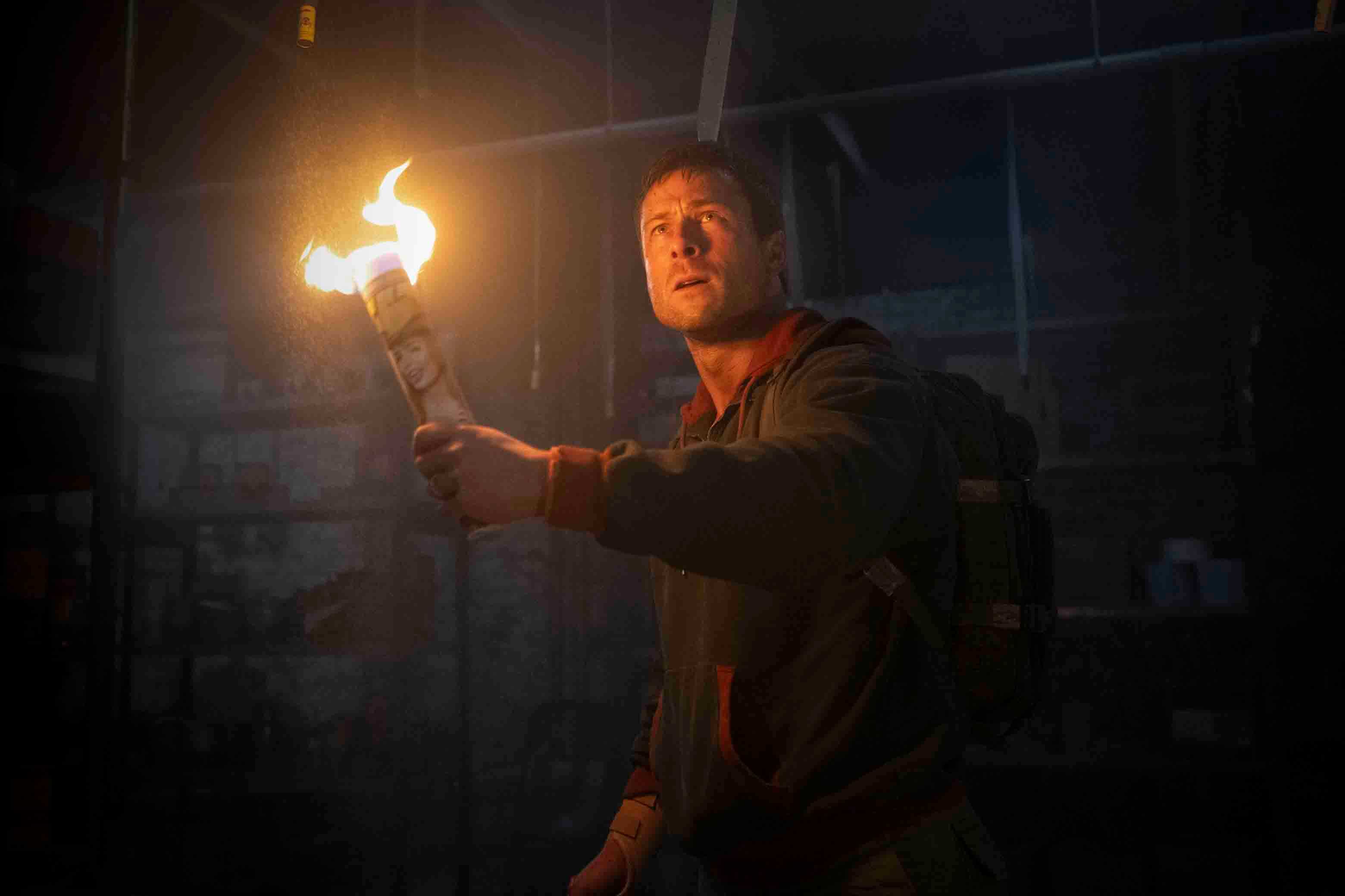 Glen Powell holds a DIY torch up in The Running Man