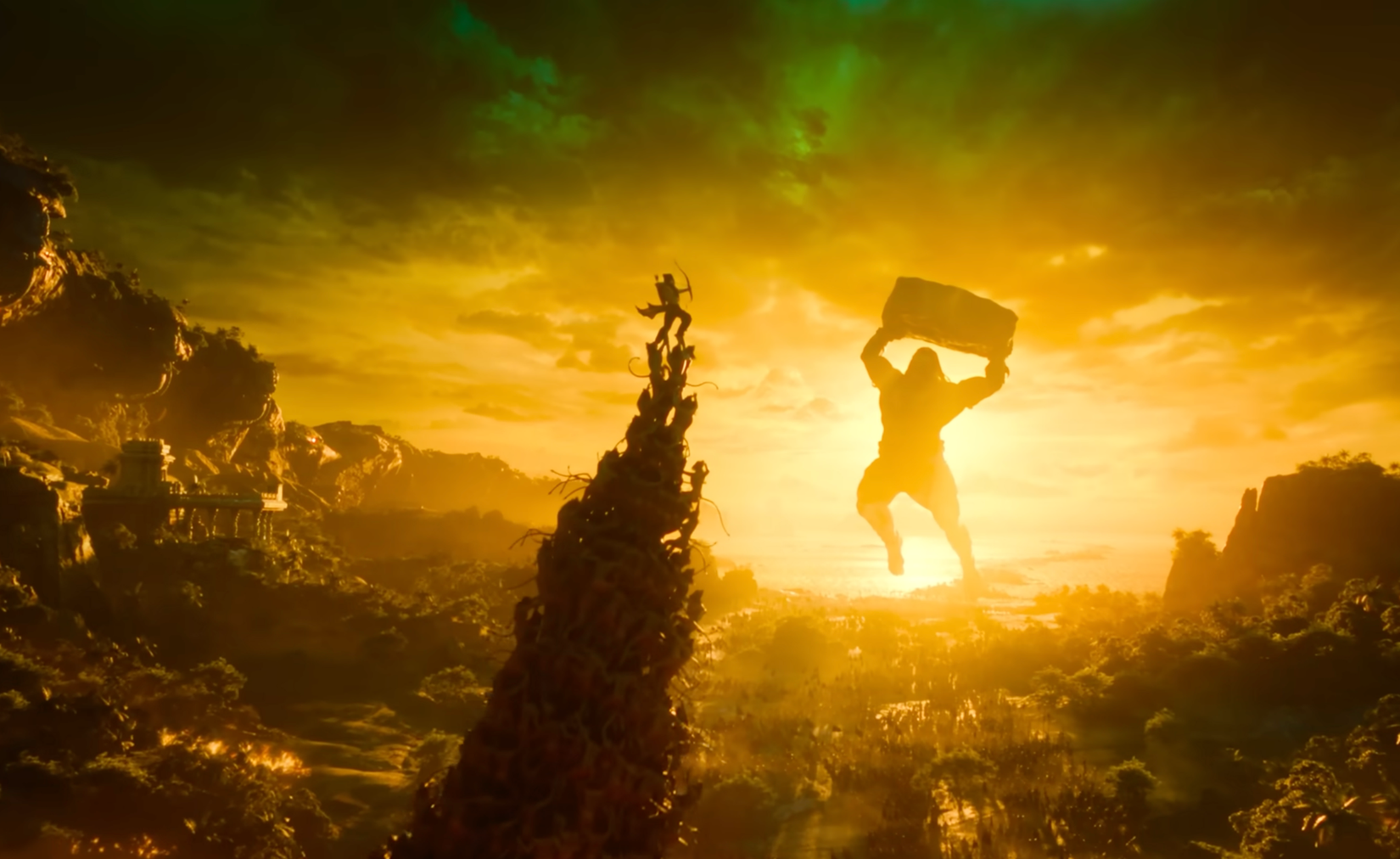 uma captura de tela do trailer de Varanasi mostrando uma pirâmide humana gigante com a pessoa no topo atirando arco e flecha contra um enorme deus mitológico