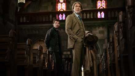 Daniel Craig, as detective Benoit Blanc, and Josh O'Connor, as a priest suspected of murder, look down the aisle of a Catholic church in a scene from Wake Up Dead Man: A Knives Out Mystery.