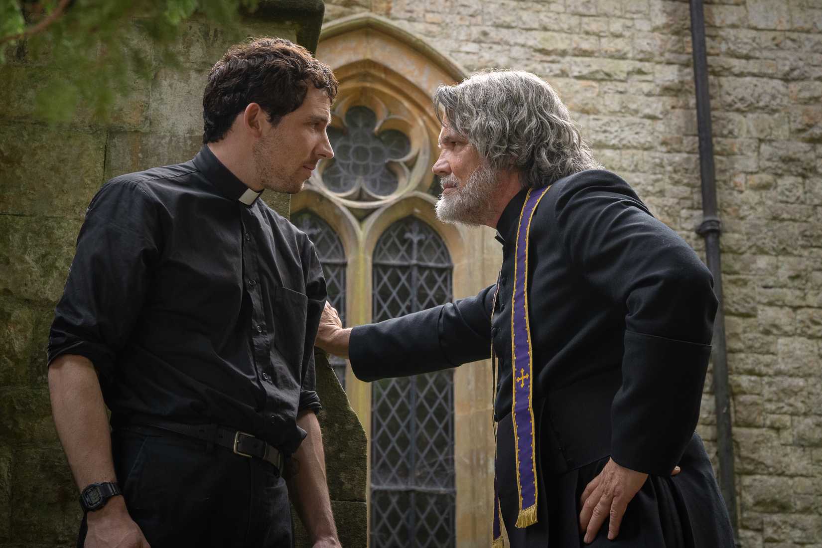 Josh O’Connor and Josh Brolin, dressed as priests, stand confrontationally close to each other in Wake Up Dead Man: A Knives Out Mystery