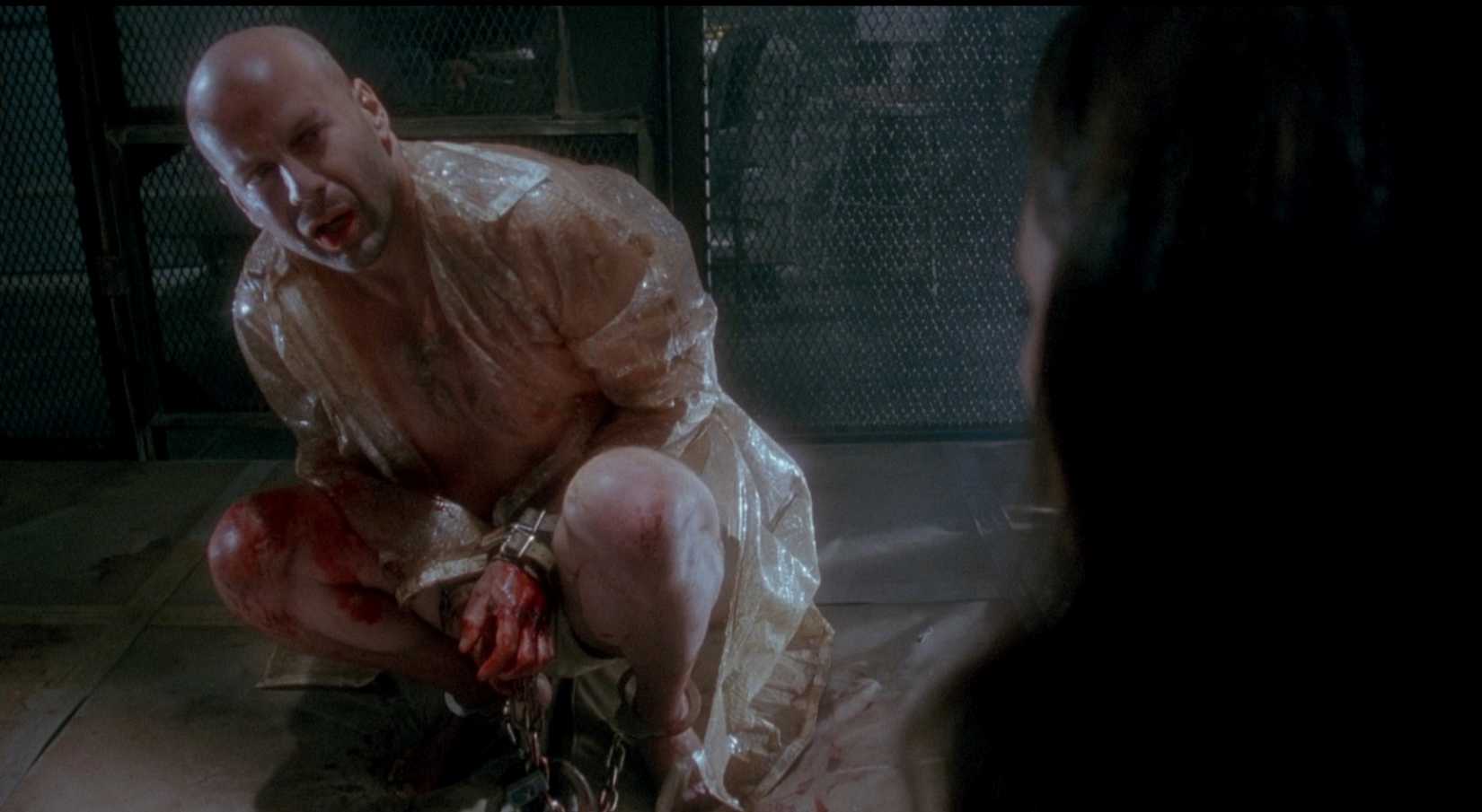 In a scene from 12 Monkeys, James Cole (Bruce Willis), a disoriented time traveler from the future covered in some kind of plastic wrapping, speaks to a psychiatrist in 1990, played by Madelaine Stowe