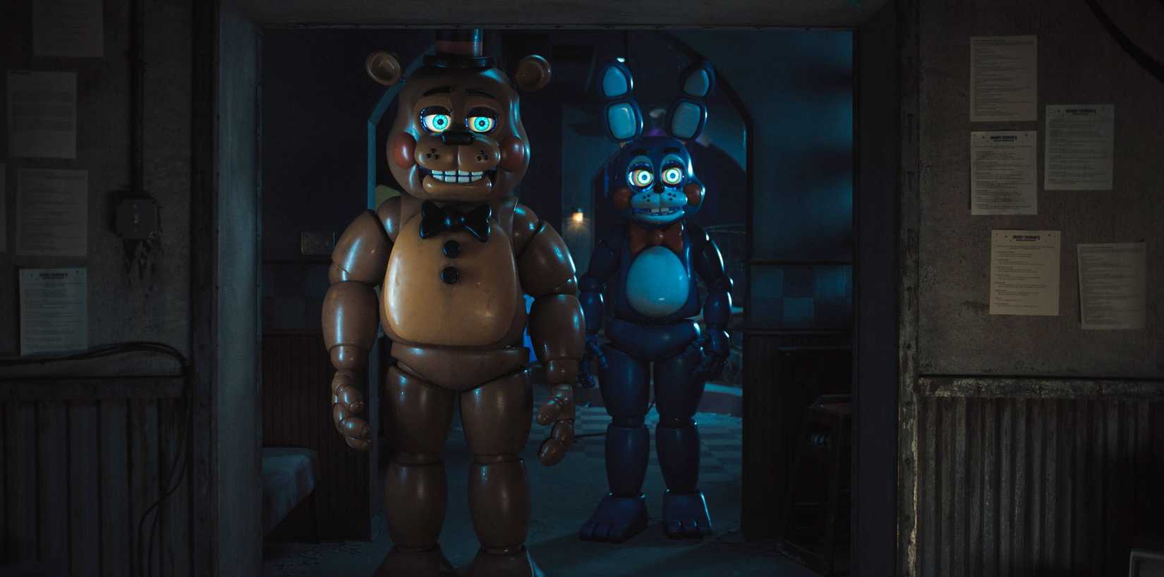 Two creepily smiling animatronic robots, a brown bear and a blue rabbit, stand in a dark hallway, eyes glowing, in Five Nights at Freddy's 2