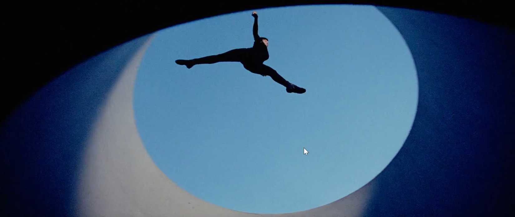 In a scene from the sci-fi movie Aeon Flux, the title character leaps across a gap between buildings, shot from below; the image looks spare and abstracted as a result. 
