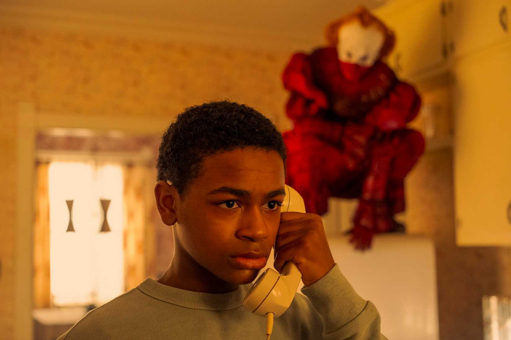 Will Hanlon (Blake Cameron James) on the phone, while Pennywise-(Bill Skarsgard) stalks him on Welcome to Derry