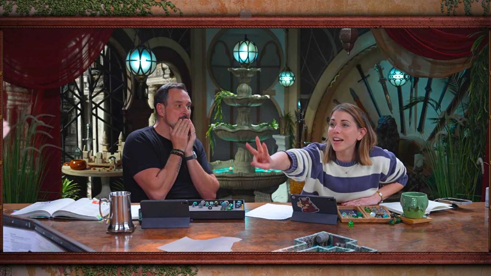 An image from Critical Role Campaign 4 Episode 10. It features Travis Willingham, his hands covering his face in shock. Beside him is Laura Bailey, who brandishes three finger towards Brennan off screen.