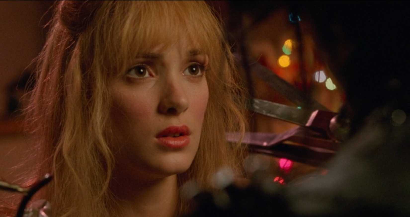 In a scene from Edward Scissorhands, the camera focuses on a close-up of Kim (Winona Ryder) as Edward attempts to touch her face with his sharp, bladed hands