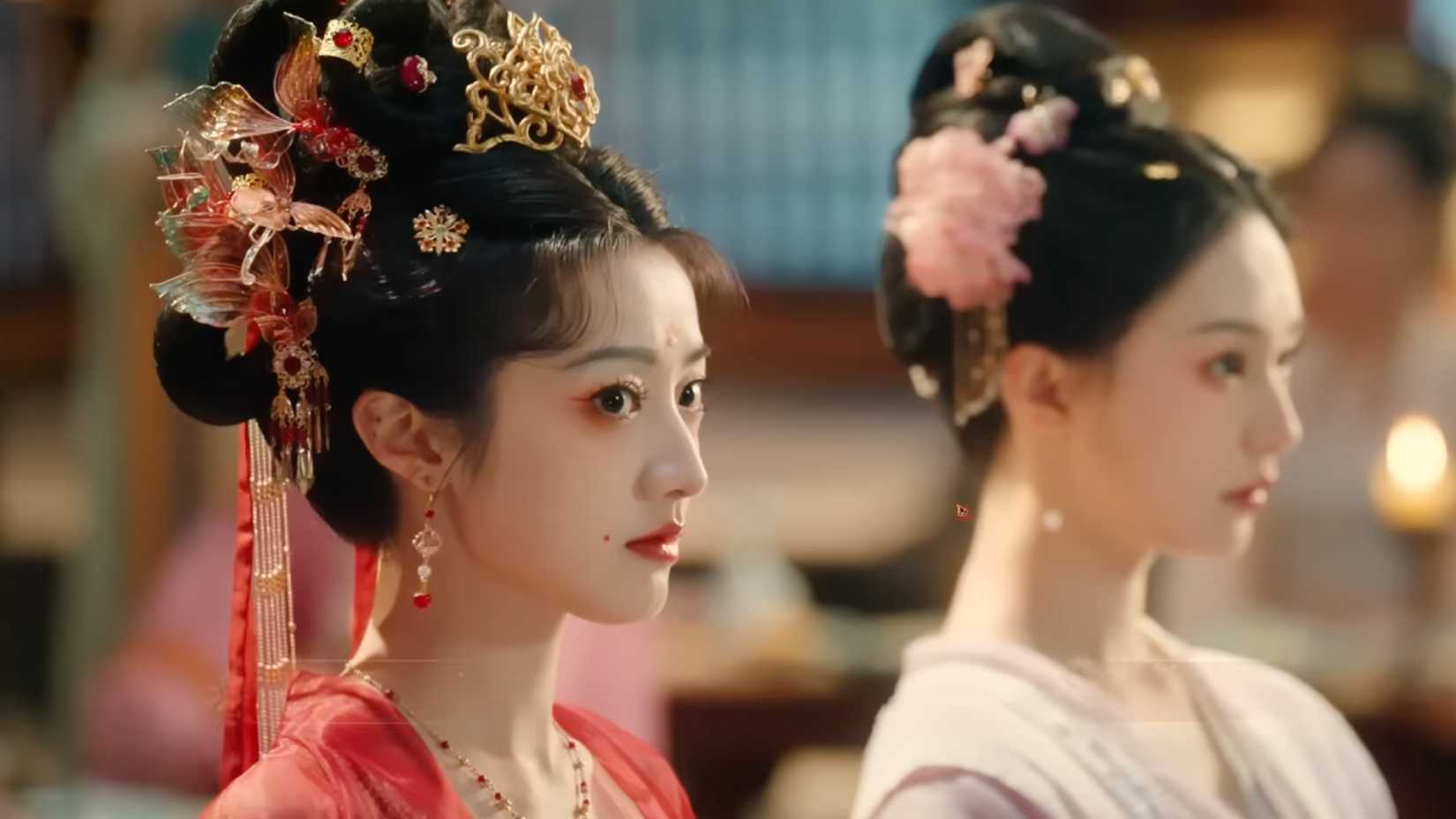 The player-character dons an elaborate red dress with matching hairpieces.