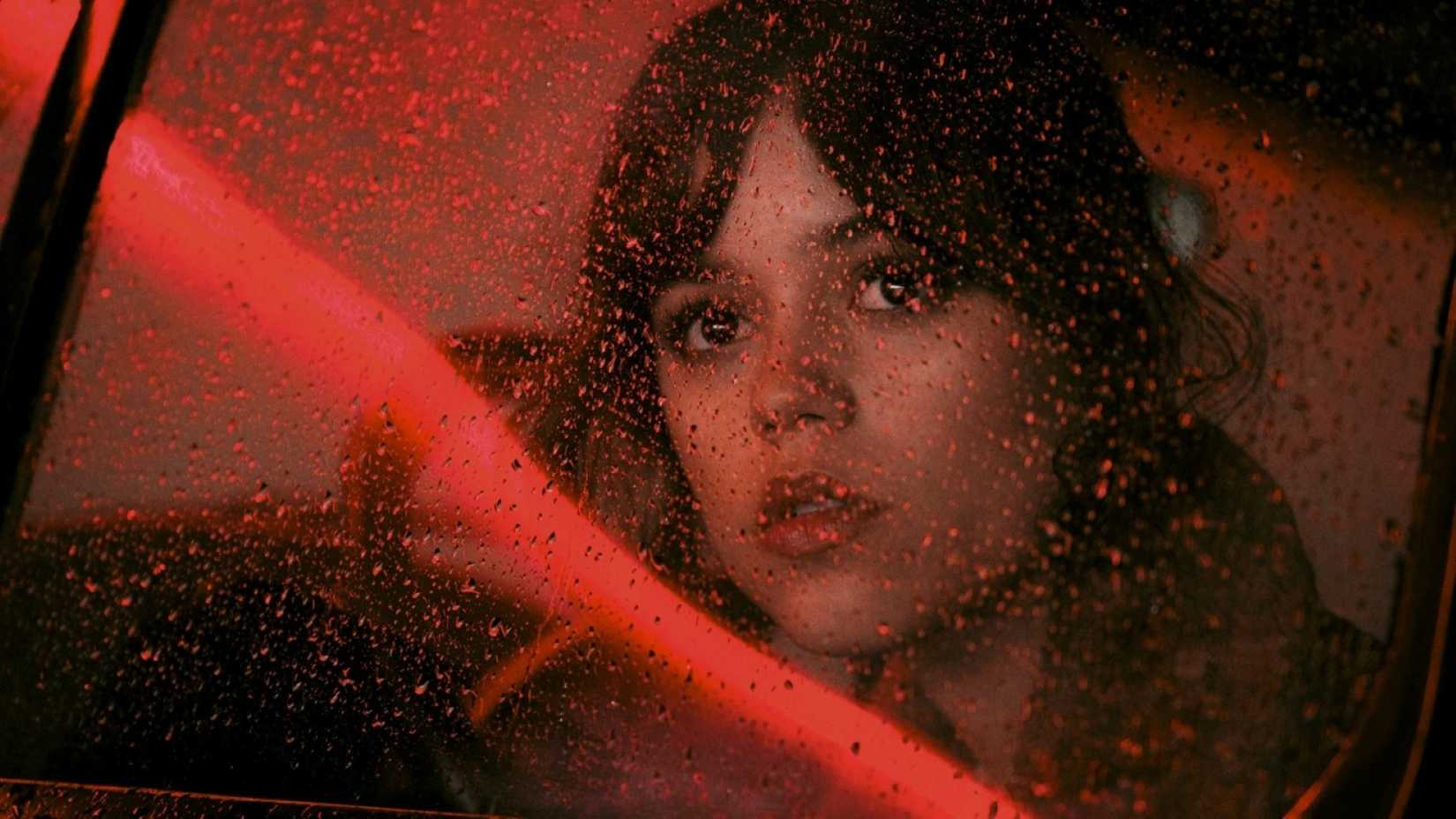 Jenna Ortega stares through a rain-dotted car window in a scene from Hurry Up Tomorrow that is far more evocative and beautiful than the movie itself.