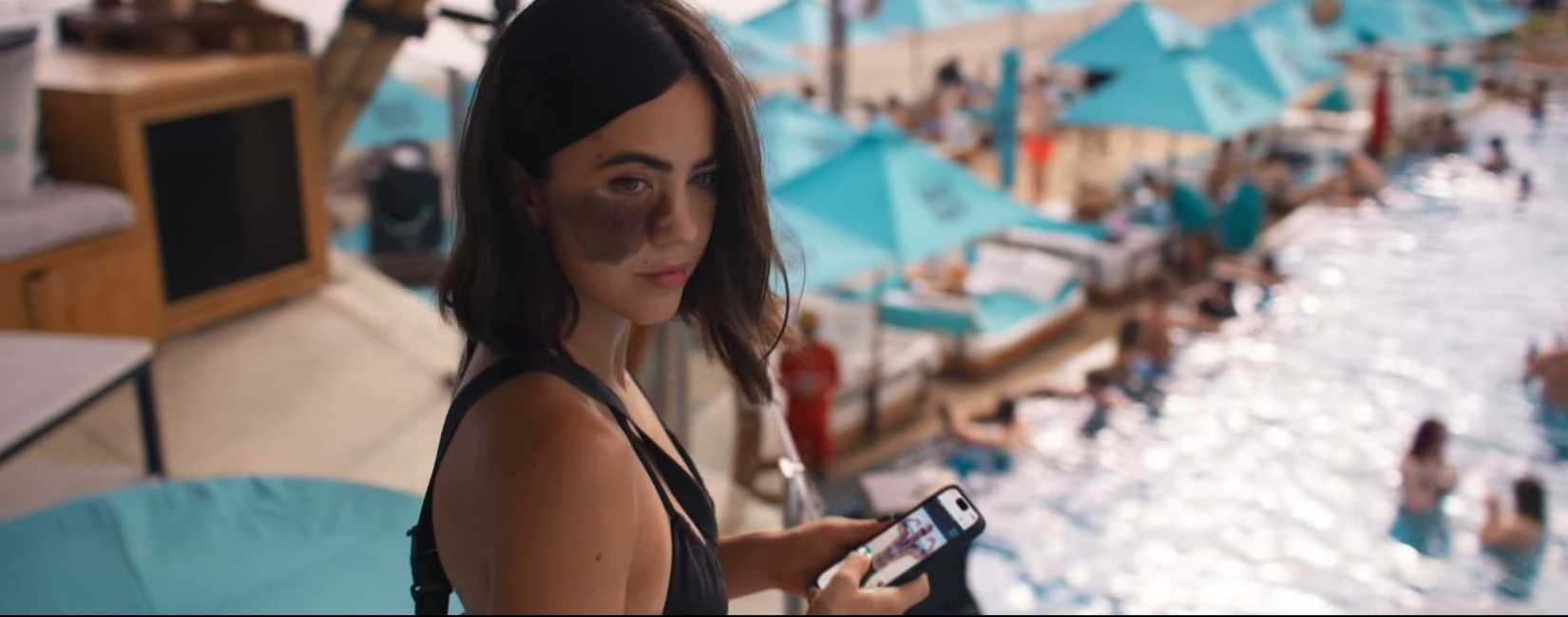 One of many shots from the movie Influencers that overlooks a pool, with CW (Cassandra Naud) consulting her phone in the foreground