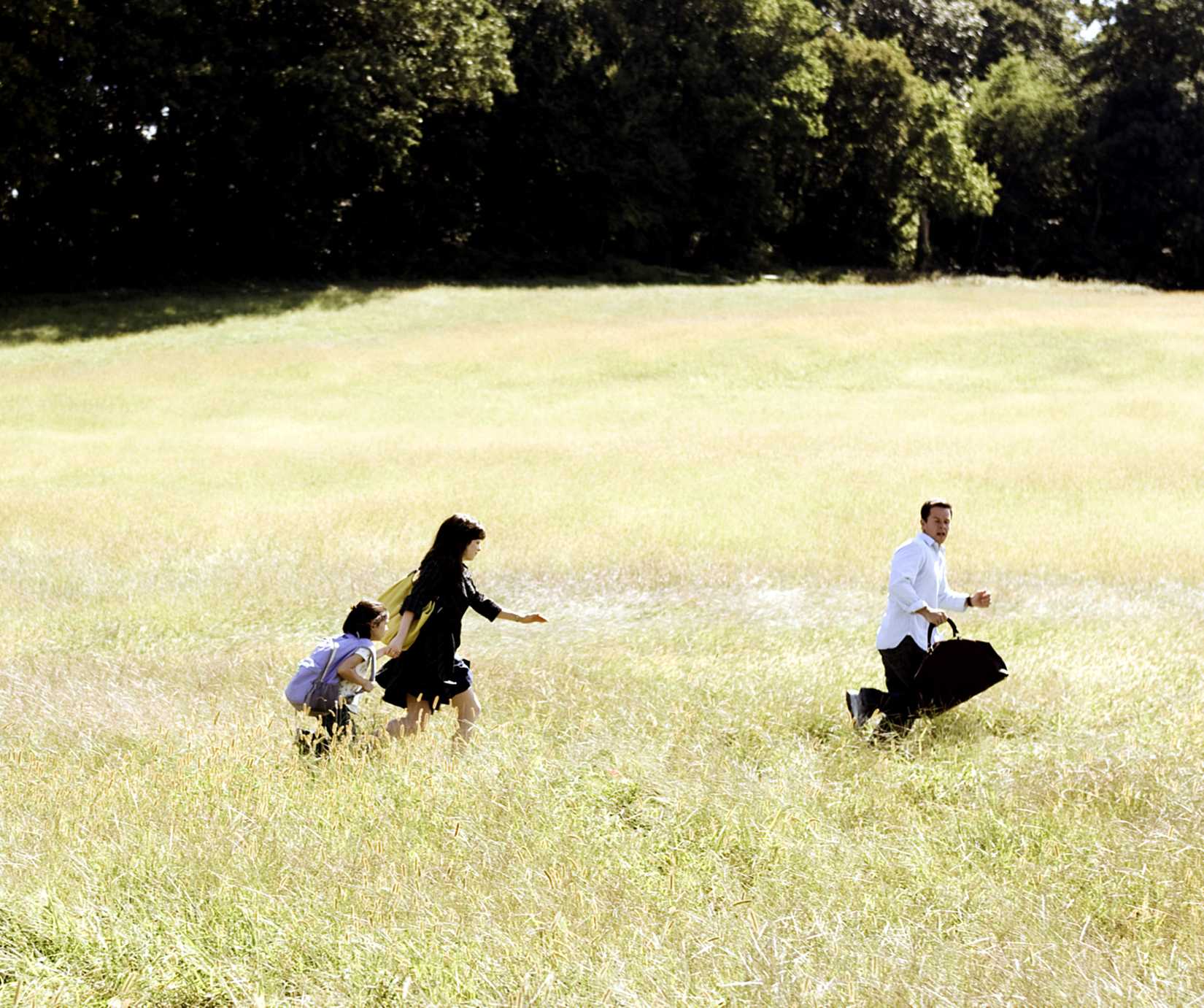Three characters run across a field to escape the breeze in M. Night Shyamalan's The Happening.