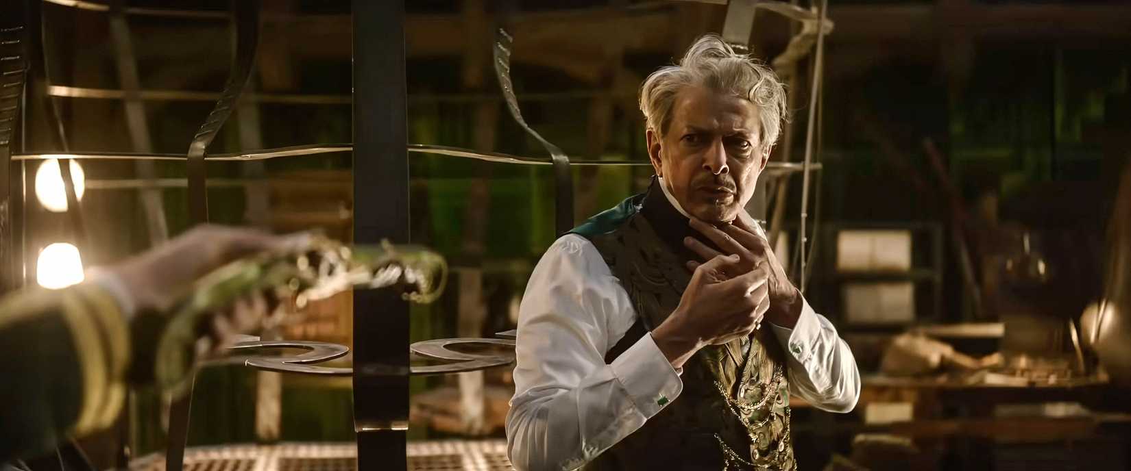 The Wizard of Oz (Jeff Goldblum) looks nervous as he's held at gunpoint by an off-screen figure in Wicked: For Good