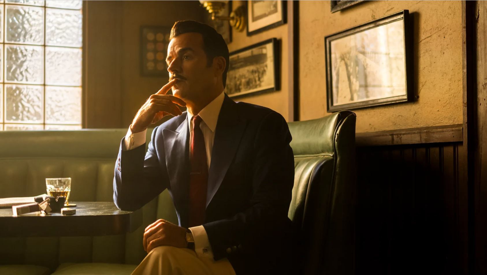 Justin Theroux in Fallout season 2, Amazon's TV adaptation of the hit RPG series. The actor, who plays tech mogul Mr. House, holds a finger to his mouth. He's sitting in a booth at a bar. 