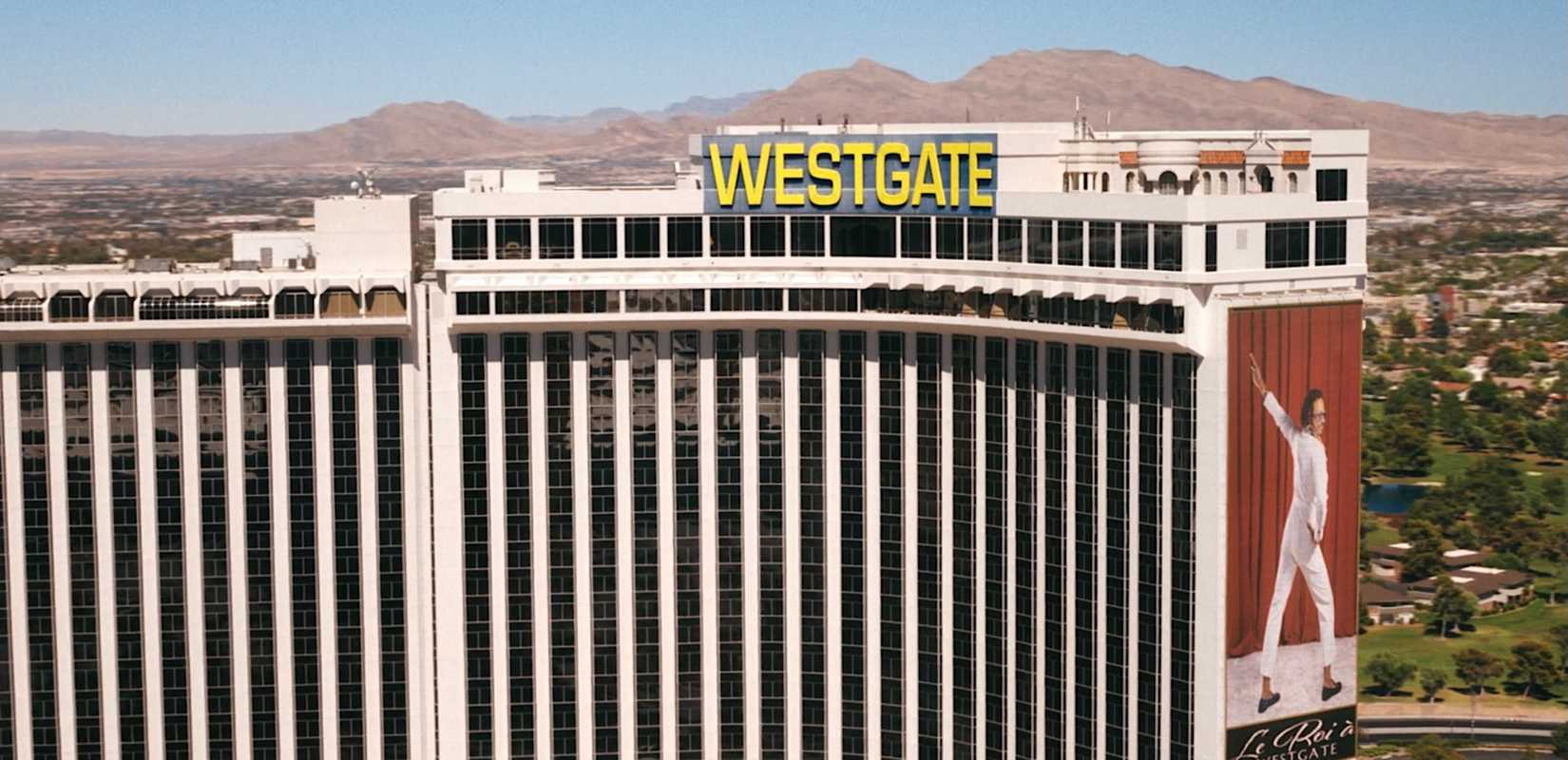 A shot of the Westgate resort and casino in Las Vegas, with a gigantic poster of Koumba Diabaté (Samba Schutte) in white, striking an Elvis-style pose, in Pluribus episode 6