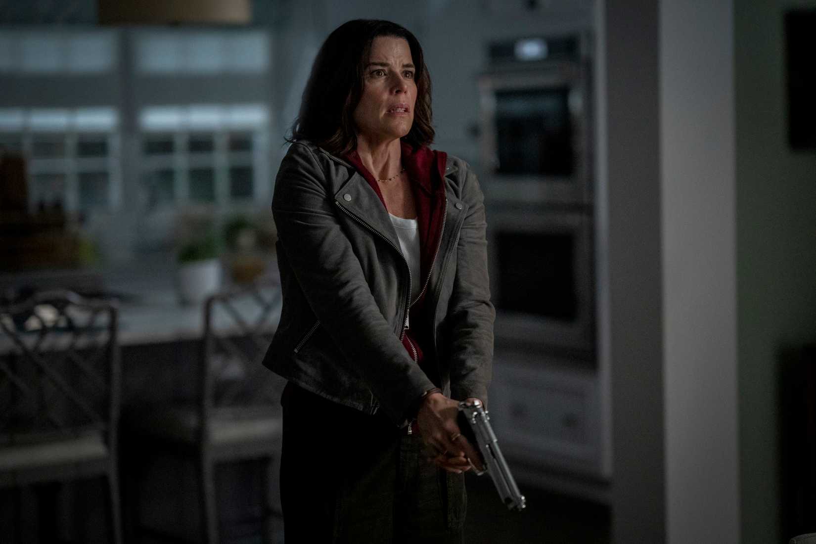 Neve Campbell's Sidney holds a pistol at guard in Scream 7