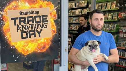a man carries a pug alongside an advertisement for GameSpot trade anything day
