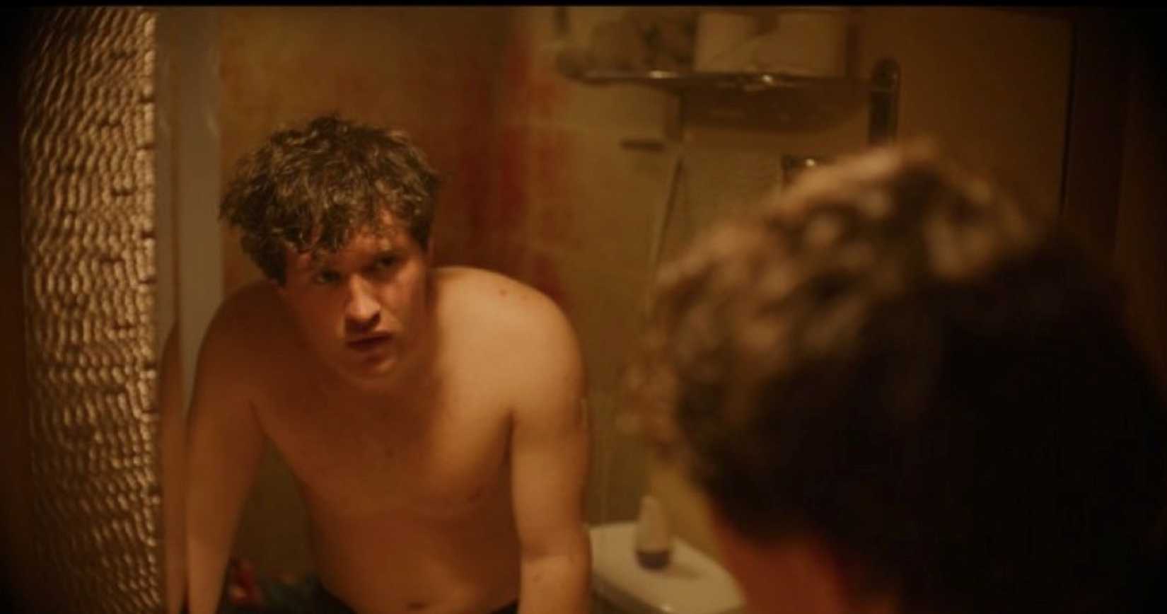 Billy (Rohan Campbell) stares at him in the mirror, shirtless, reflecting on the possible misdeeds he's done while dressed up as Santa in the 2025 version of Silent Night, Deadly Night