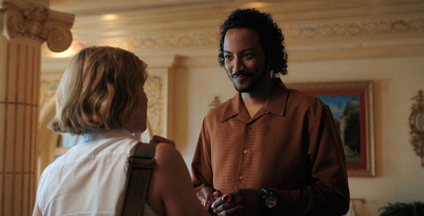 Koumba Diabaté (Samba Schutte) smiles warmly at Carol (Rhea Seehorn) in Pluribus episode 6