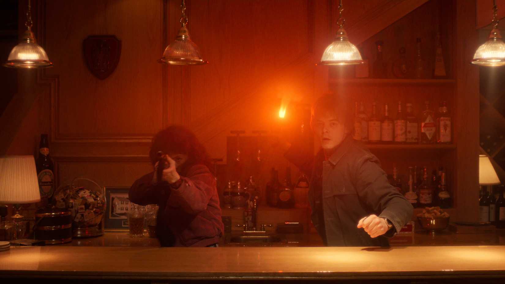 Nancy Wheeler (Natalia Dyer) points a shotgun and Jonathan Byers (Charlie Heaton) throws a Molotov cocktail into the Turnbow basement in Stranger Things season five.