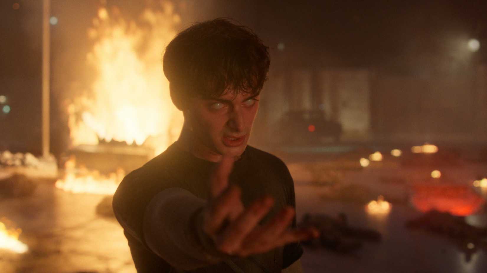 Will (Noah Schnapp) holds out his hand near a rift with fire in the background in Stranger Things season 5