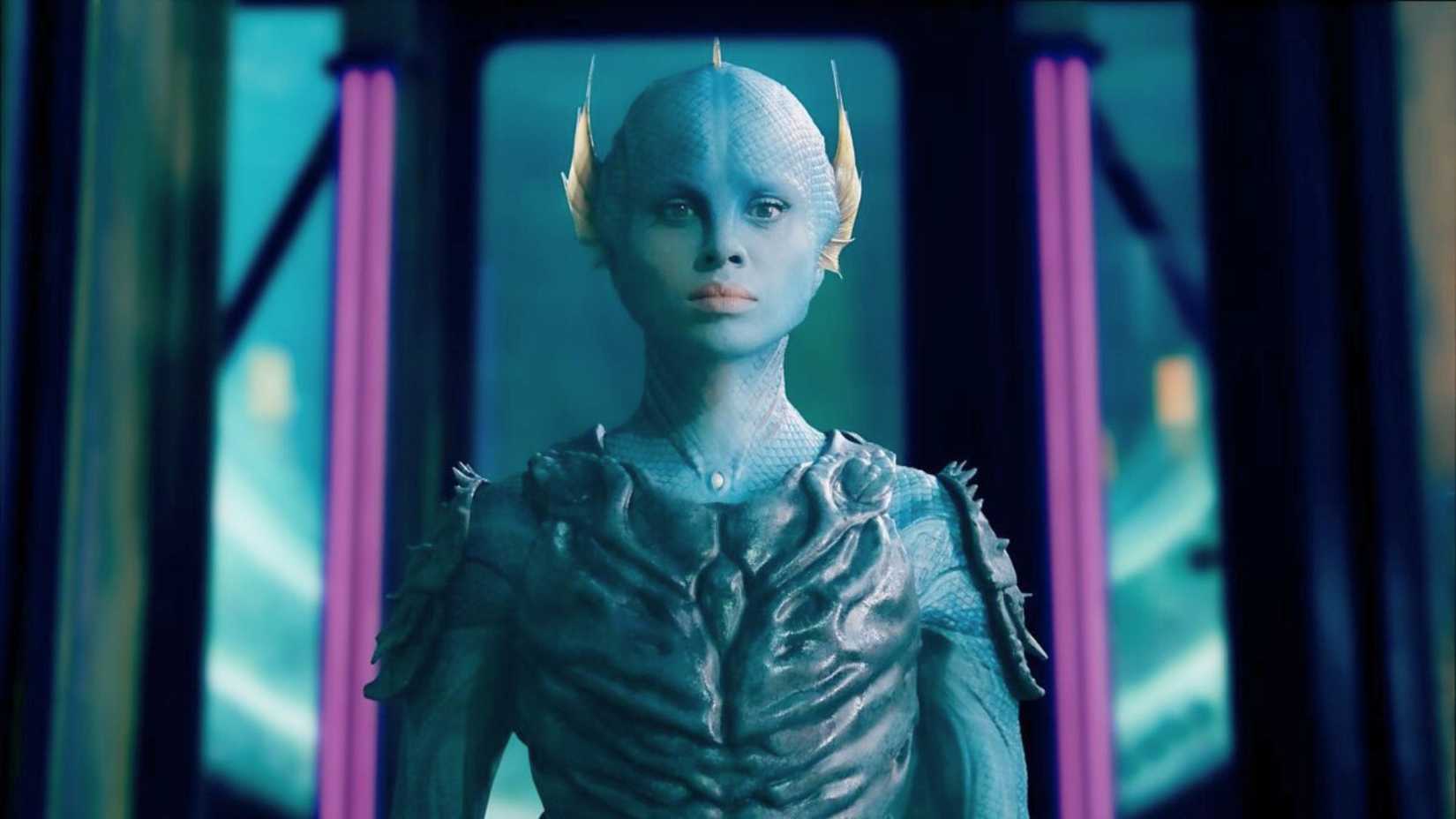 Gugu Mbatha-Raw plays Salt in The War Between the Land and Sea. She is a blue-skinned, fish person, who stares ahead surrounded by an alien spaceship.