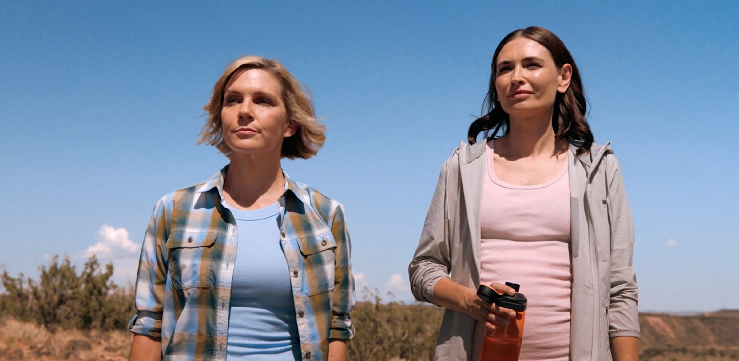 Carol (Rhea Seehorn) and Zosia (Karolina Wydra) stand side by side on an arid cliff in Pluribus episode 8