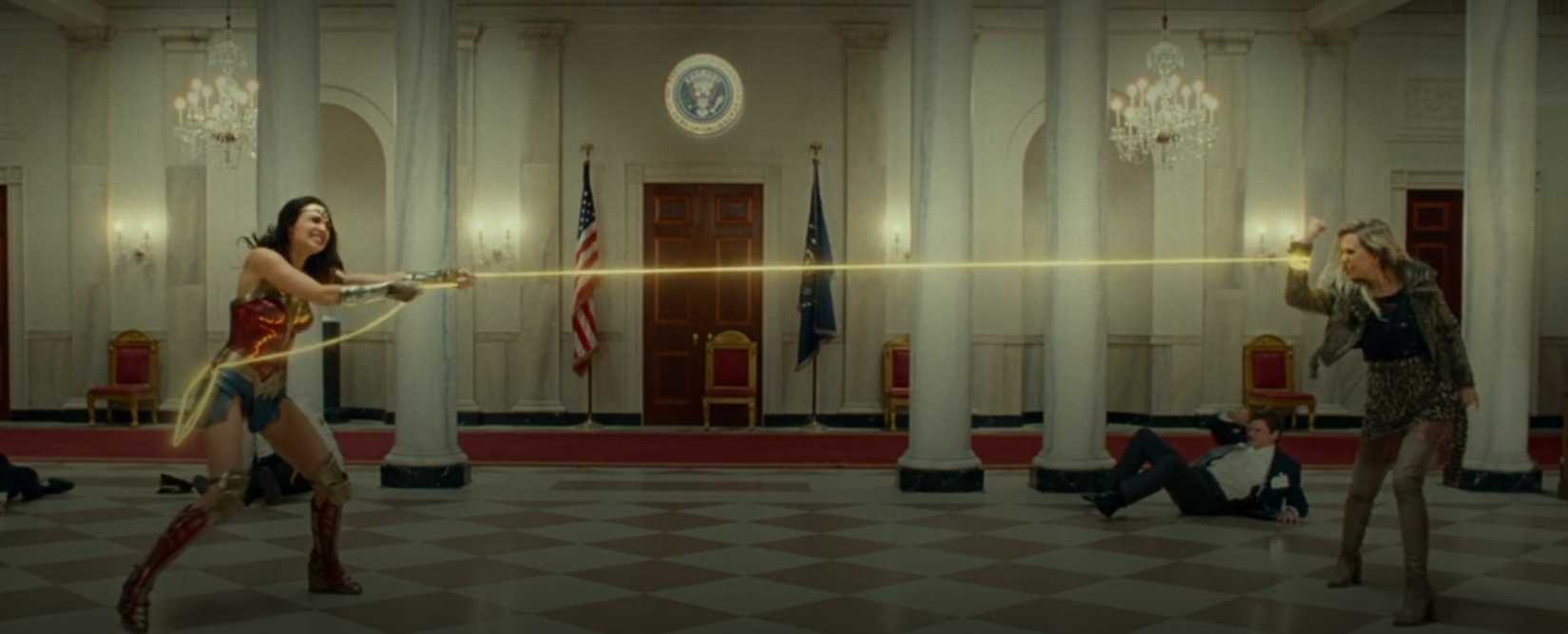 Diana (Gal Gadot) battles Barbara (Kristen Wiig) on opposite sides of a wide-shot frame, at the White House no less, during a scene from Wonder Woman 1984