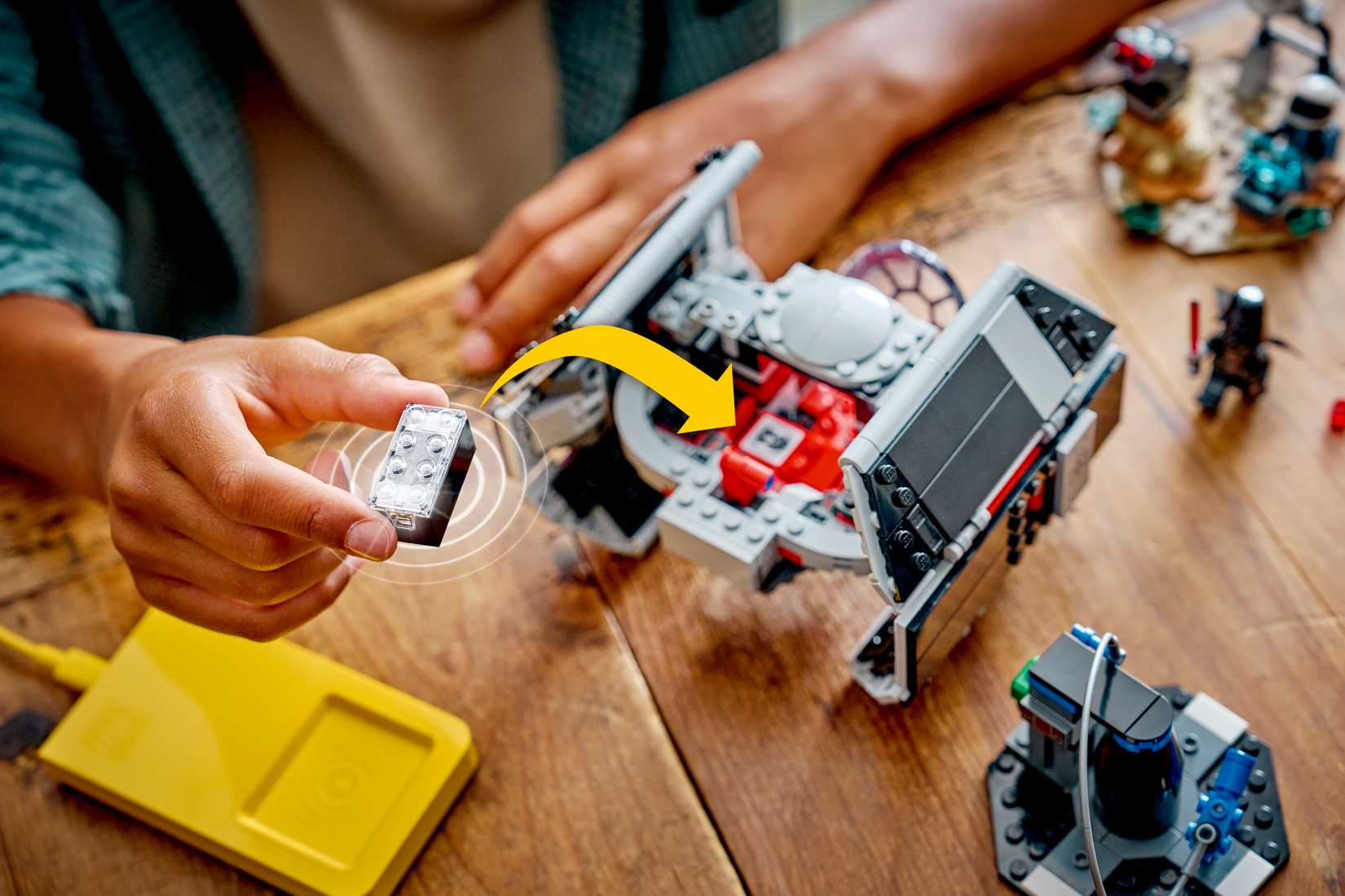 A child inserts a Lego Smart Brick into a Lego Darth Vader TIE Fighter set