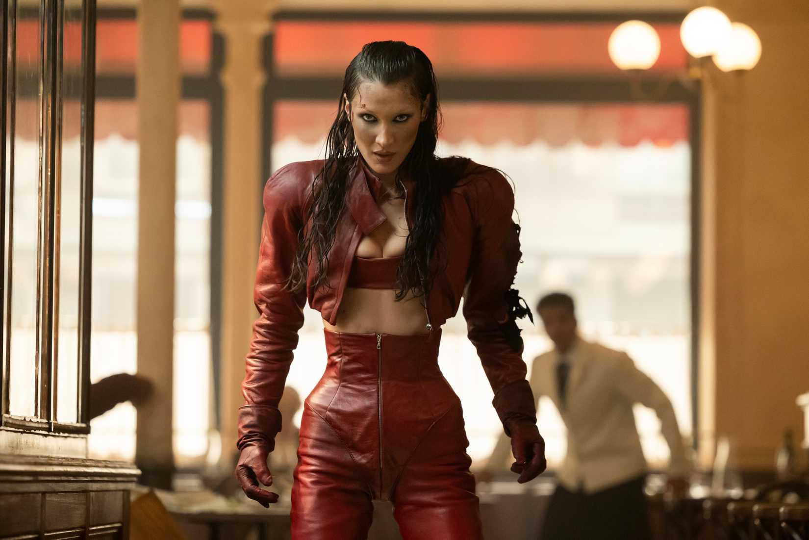 A feral-looking woman in red leather snarling in a scene from The Beauty