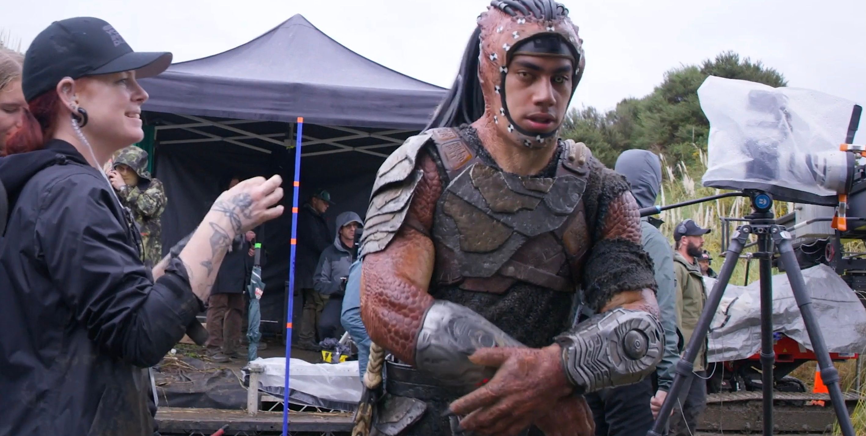 Dimitrius Schuster-Koloamatangi on the set of Predator: Badlands wearing a Predator head cowl with his human face visible.