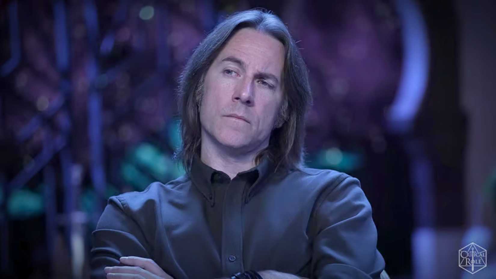 Images from Critical Role Campaign 4, Episode 12. It features Matthew Mercer wearing a black shirt and arms crossed over his chest.