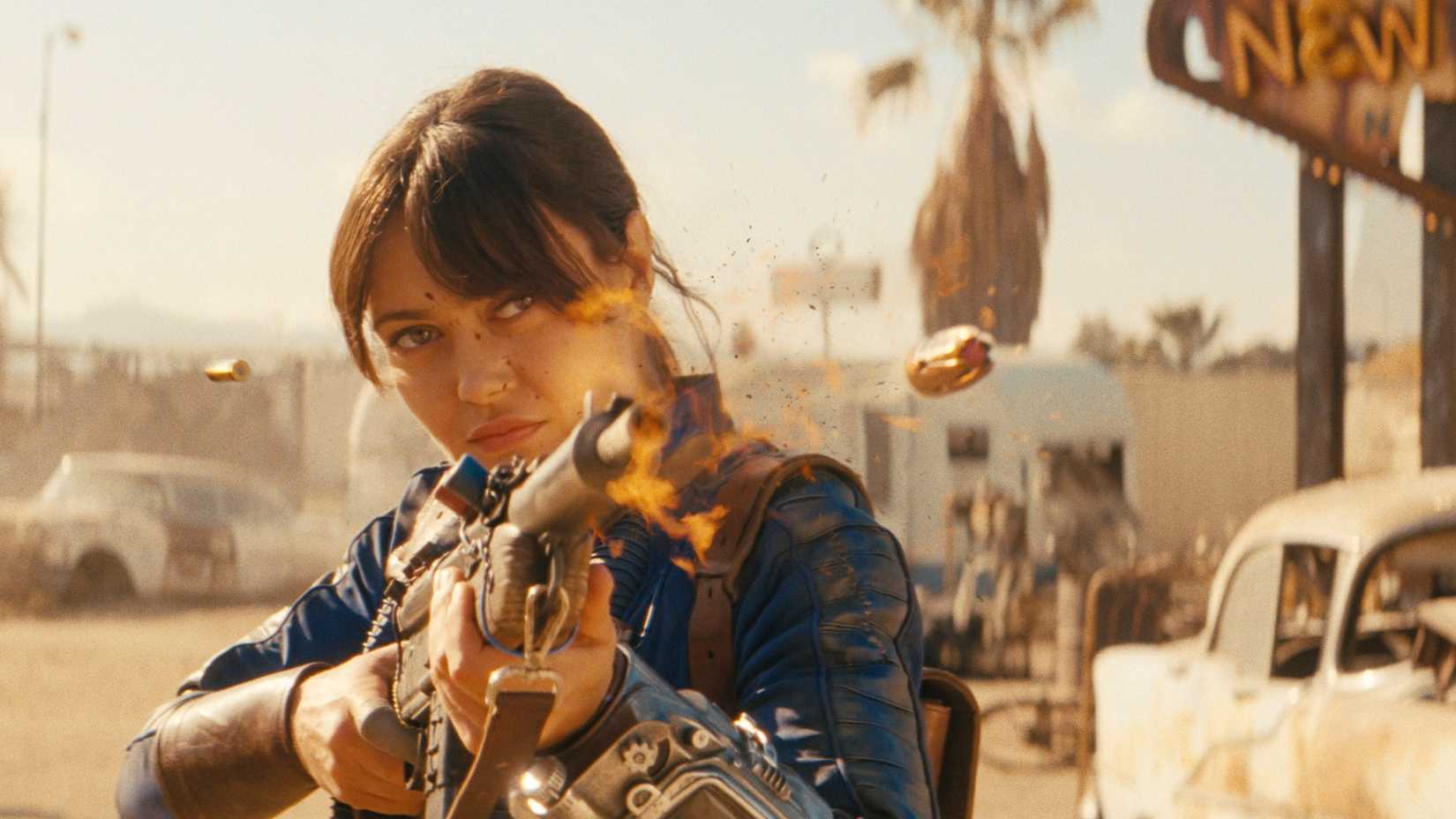 Lucy (Ella Purnell) fires a gun in front of the New Vegas sign in Fallout season 2