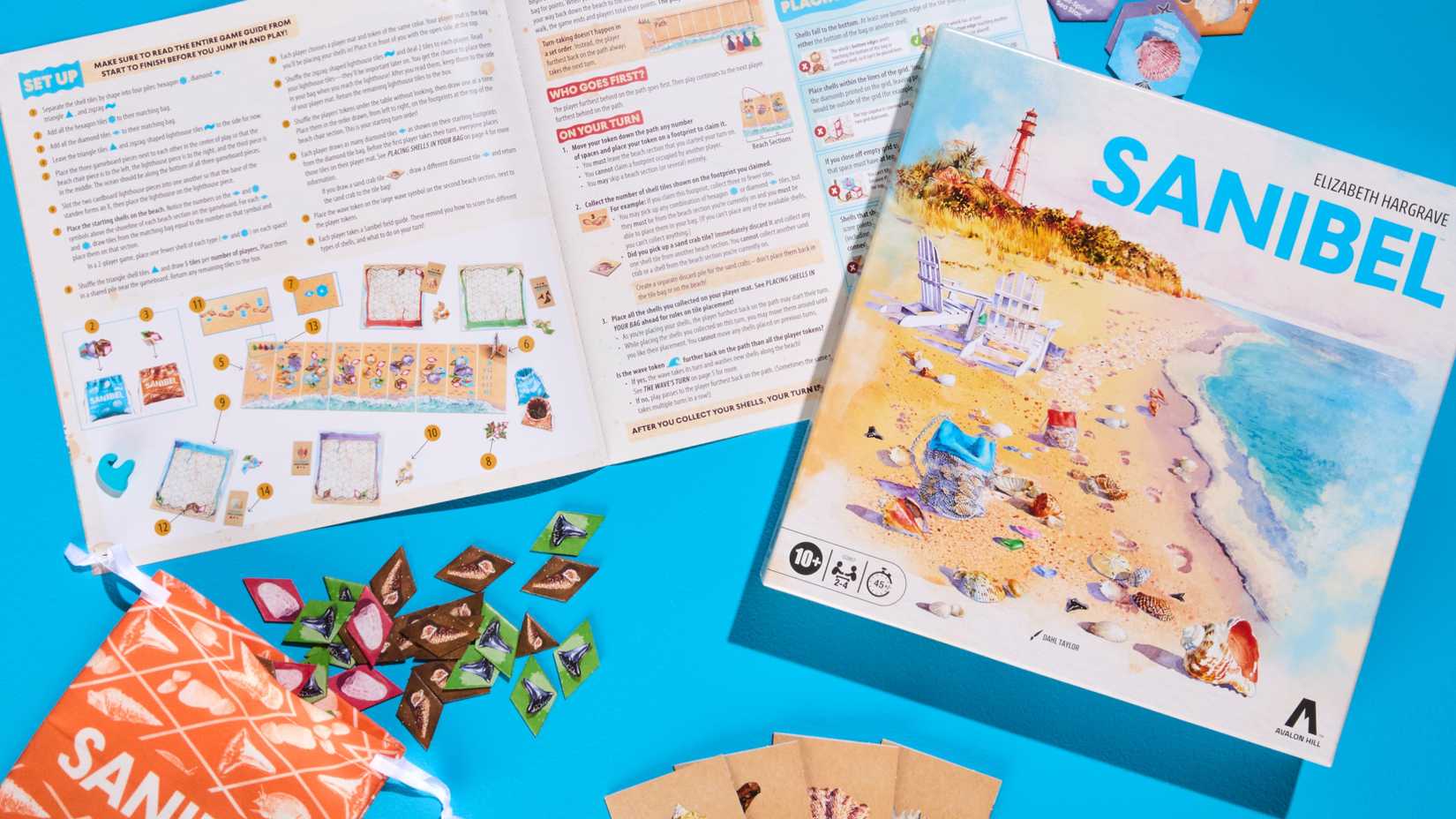 The cover of Elizabeth Hargrave's board game Sanibel next to the rulebook and component bag with tiles spread out