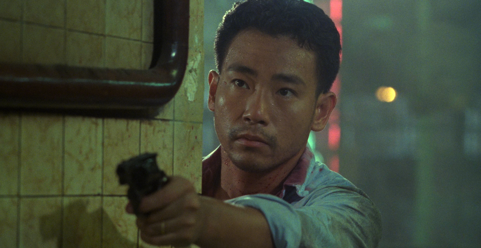 Benny points a gun at the smugglers during the teahouse shoot-out in Hard Boiled