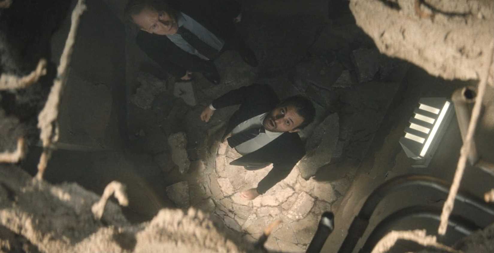 Agent Cleary (Arian Moayed) stares up, open-mouthed, through a human-sized hole in the concrete ceiling of a prison cell in Wonder Man