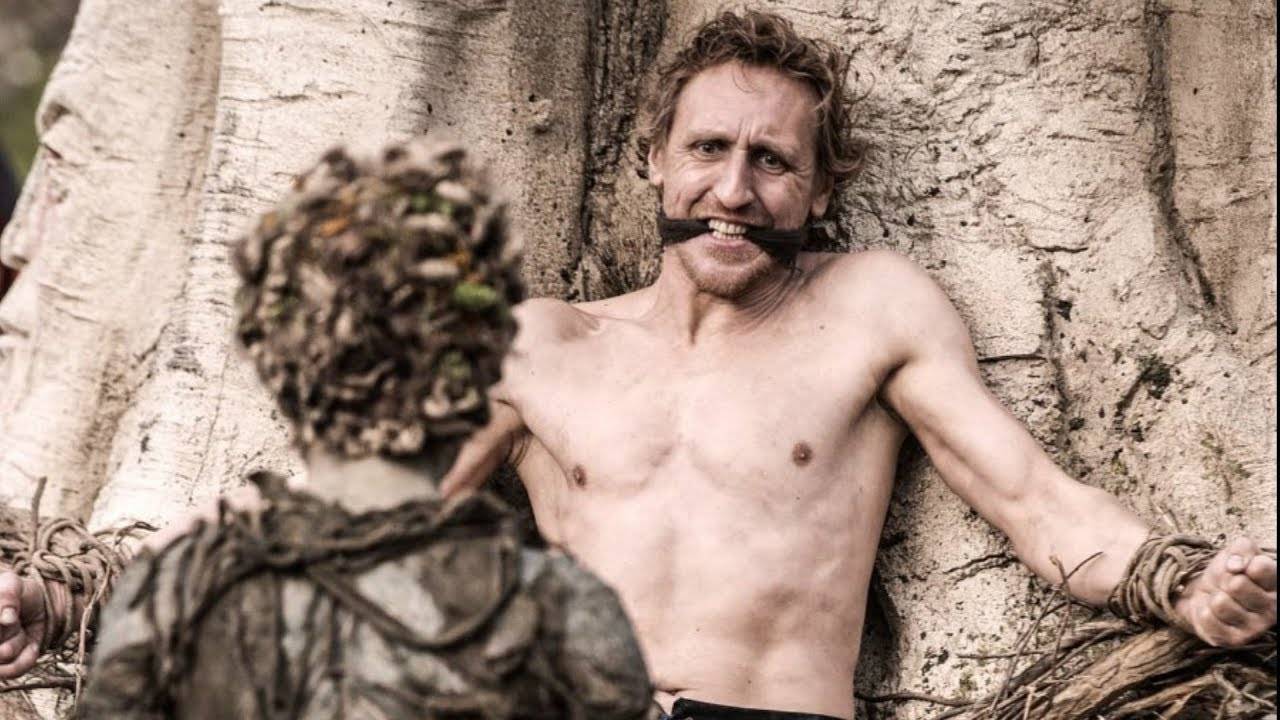 Image of a scene depicting the origin of the Night King in Game of Thrones. A shirtless man is gagged and bound to a tree while a non-human magical creature prepares to transform him