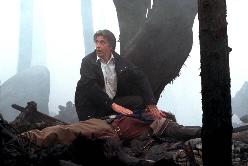 Al Pacino crouches over a man lying on the ground in a misty forest in Christopher Nolan's Insomnia