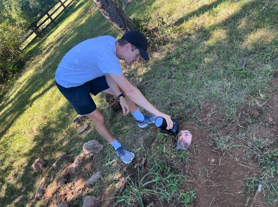 Albert Birney checking footage on a DSLR while buried underground up to his face