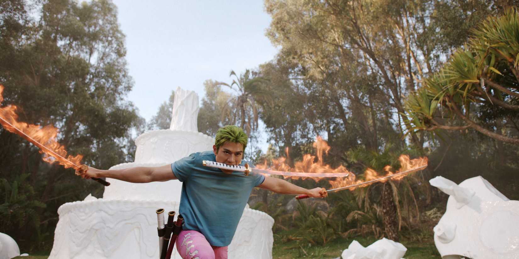 Dans une scène tirée de One Piece Into the Grand Line, Zoro manie des épées enflammées, avec un gâteau géant en arrière-plan.