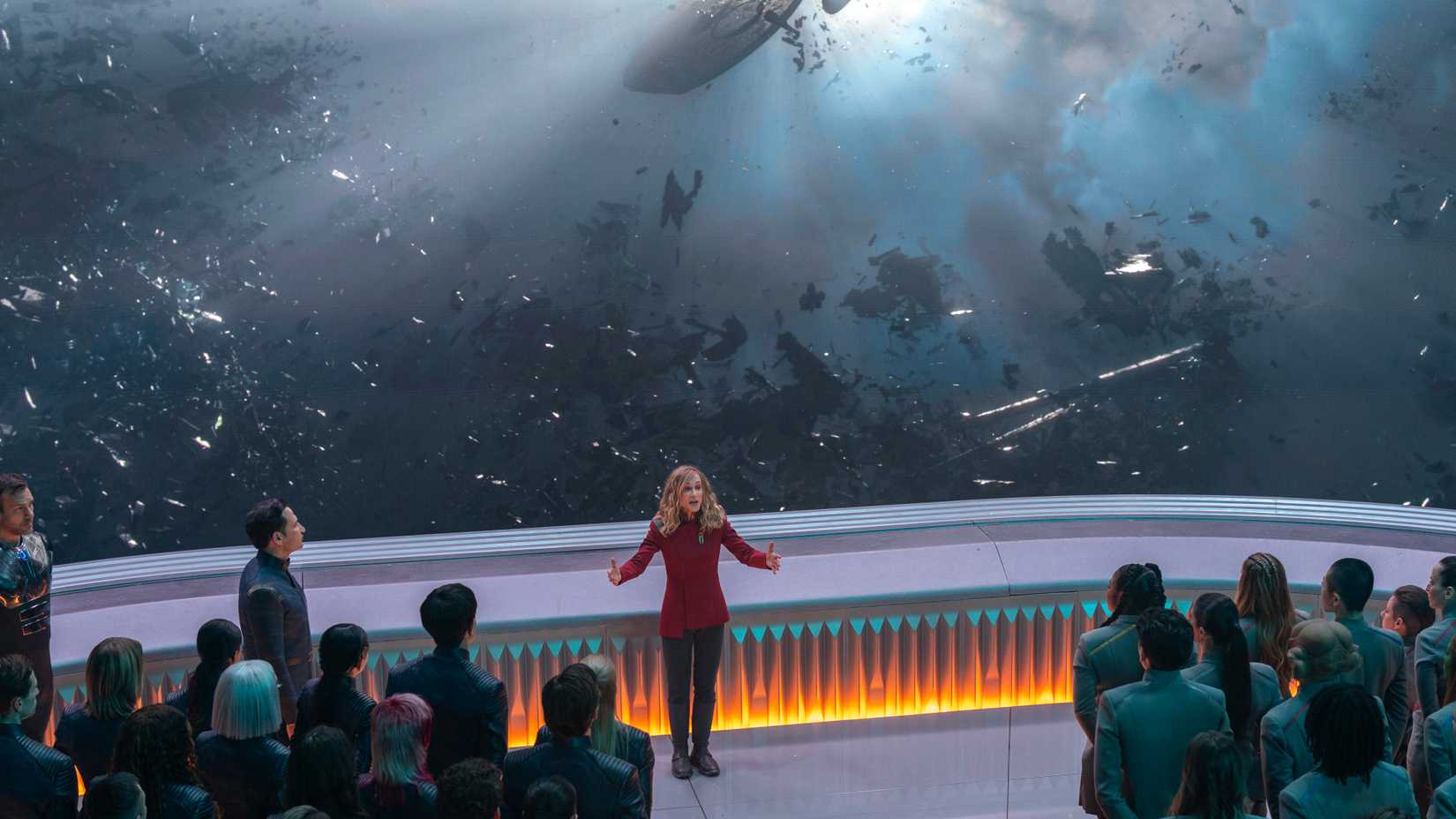 Nahla Ake (Holly Hunter) gives a presentation to the students at Starfleet Academy in front of a giant window showing Starfleet ships destroyed in the Burn
