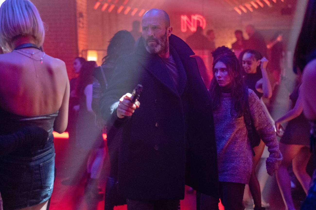 Jason Statham runs through a dimly lit nightclub, holding a gun, in Shelter