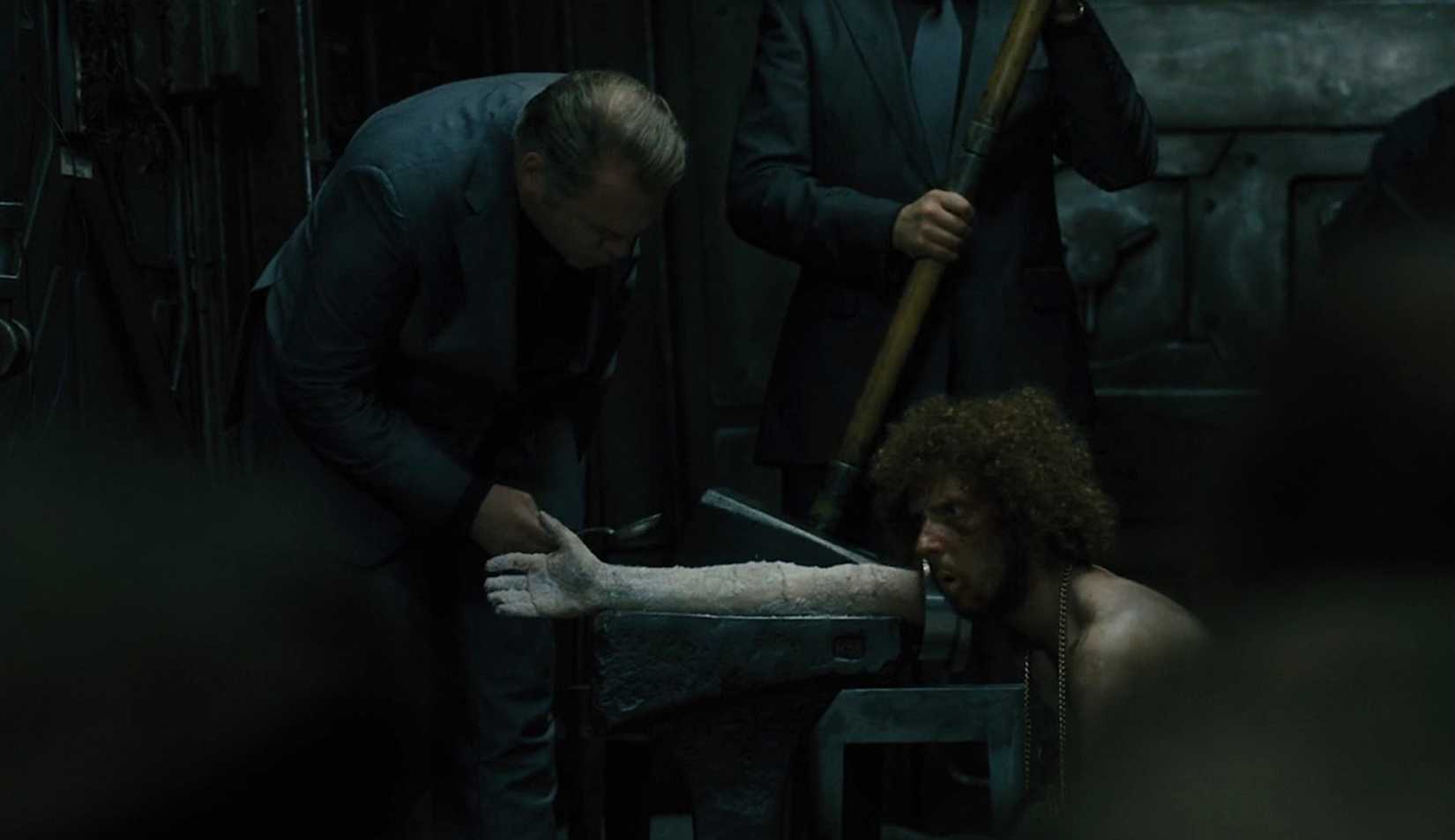Andrew kneels, arm outstretched and frozen solid, in Snowpiercer (2014)