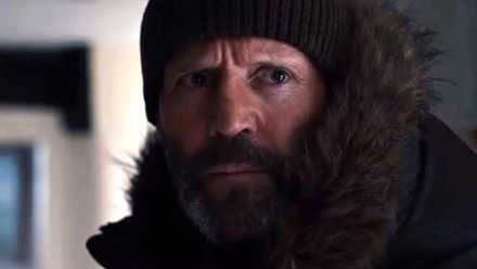 Jason Statham in a close-up, in a furry coat, watchcap, and heavy beard in Shelter