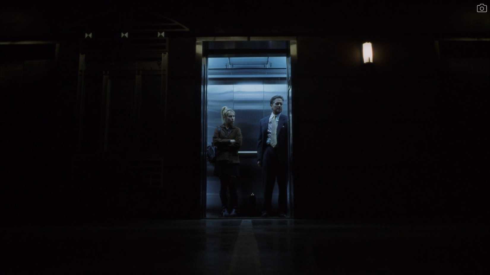 In a striking wide shot from David Fincher's The Game, Michael Douglas and Deborah Kara Unger stand in a blue-lit elevator, otherwise surrounded by darkness