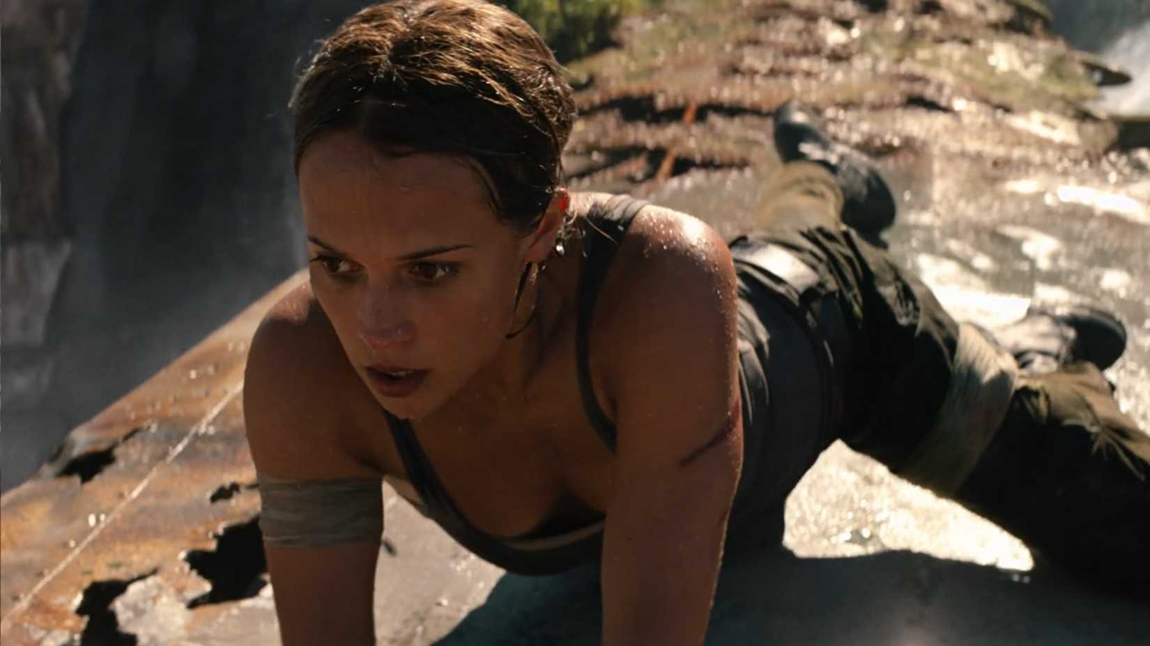 Lara Croft (Alicia Vikander) balances on the rusty wing of a plane perched above a waterfall, shown here in close-up, in a scene from Tomb Raider (2018)