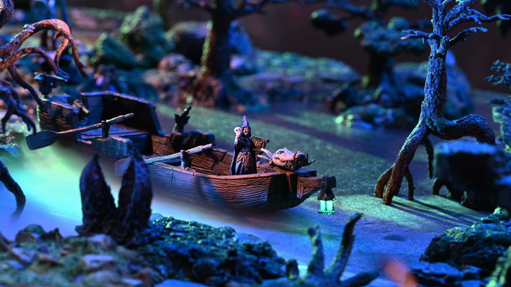 A wizard on a boat with a lantern on it sailes through a swamp made with Dwarven Forge terrain